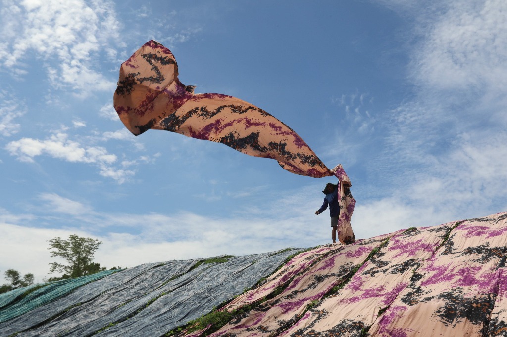 Surakarta. Un trabajador coloca una tela conocida localmente como "tela de playa", utilizada para confeccionar prendas de vestir para mujeres musulmanas, para que se seque en la orilla de un río en esta urbe indonesia. Foto Afp / Garry Lotulung
