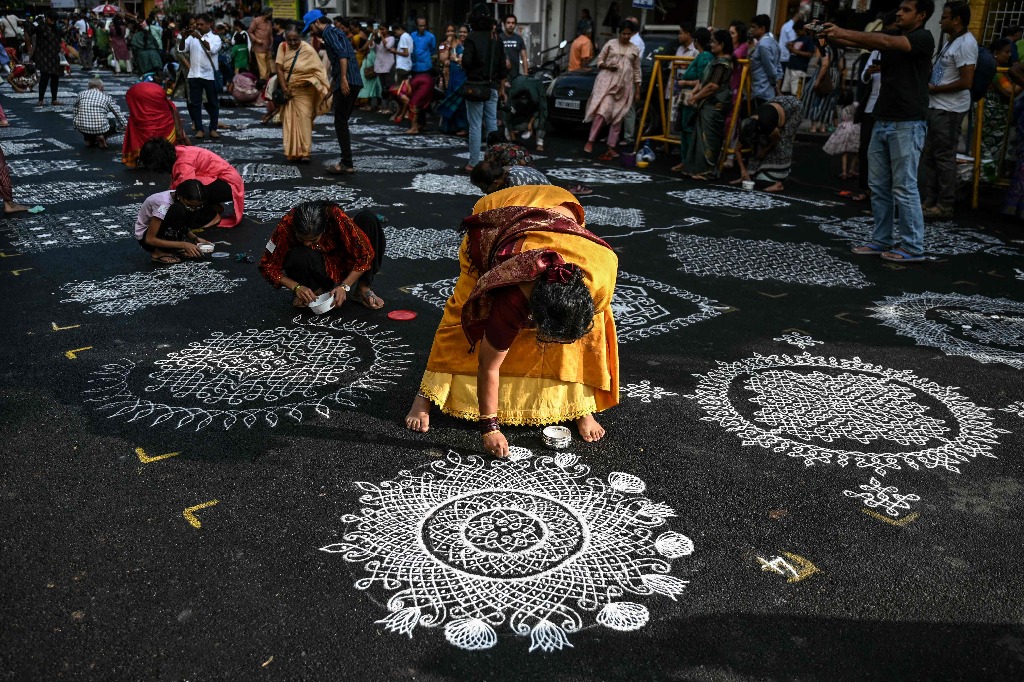 Chennai. Varias personas participan en un concurso en el que dibujan distintos 'Kolam', un arte decorativo tradicional de la India en el que utilizan harina de arroz, polvo de piedra blanca o tiza. Foto Afp / R. Satish Babu
