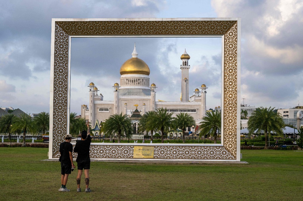 Bandar Seri Begawan. Turistas tailandeses toman fotografías de la mezquita del sultán Omar Ali Saifuddien, en la capital de Brunei. Foto Afp / Mohd Rasfan