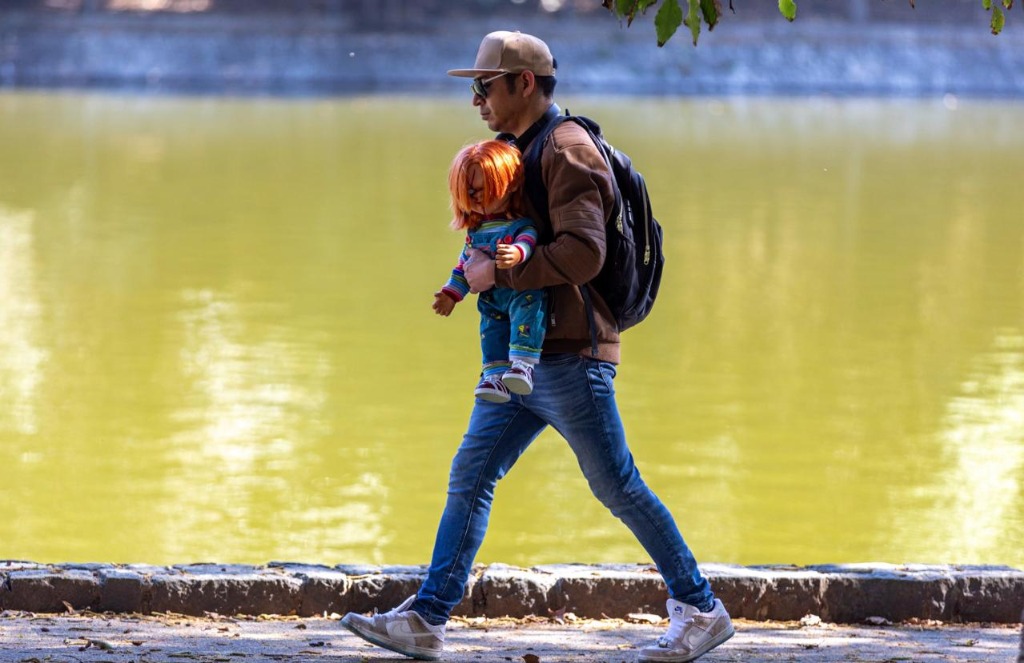 Ciudad de México. Un hombre camina con un muñeco ‘Chucky’ a las orillas del lago del Bosque de Chapultepec, en la alcaldía Miguel Hidalgo. Foto Pablo Ramos / ‘La Jornada’