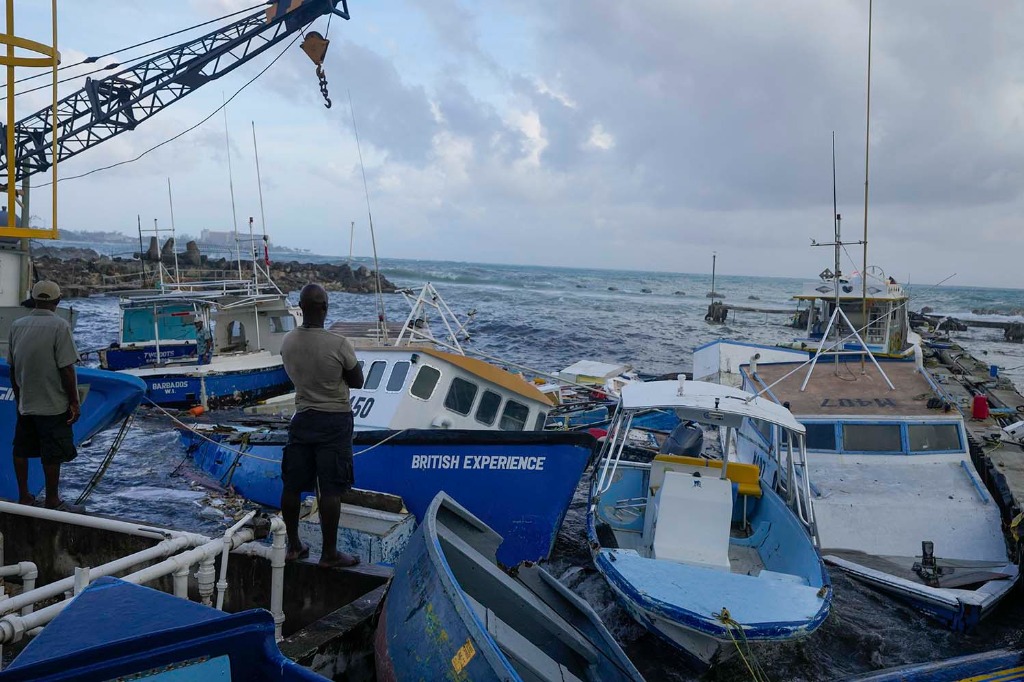 Pescadores observan los barcos dañados por el huracán Beryl en Bridgetown Fisheries en Barbados. Foto: AP