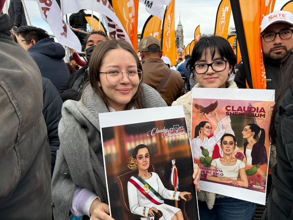 Jóvenes muestran imágenes de la Presidenta de México, Claudia Sheinbaum, mientras esperan que inicie la ceremonia en el primer cuadro de la Ciudad de México. Foto Luis Castillo
