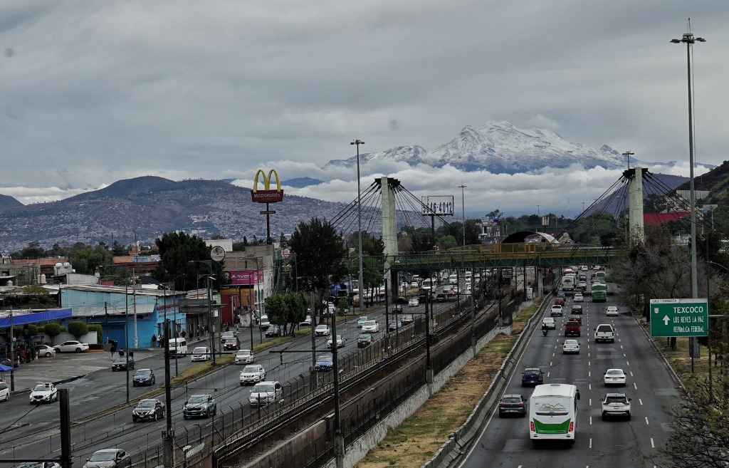 Ciudad de México. El volcán Iztaccíhuatl visto desde la alcaldía Iztapalapa, donde peatones se subieron a un puente peatonal para llevarse el recuerdo del paisaje. Foto Jair Cabrera Torres