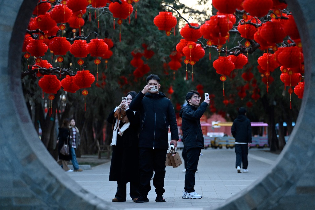 Pekín. Unas personas se toman fotos frente a faroles rojos colgados de los árboles con motivo del festejo del próximo Año Nuevo Lunar de la Serpiente, en un parque de la capital china. Foto Afp / Zhao Wang